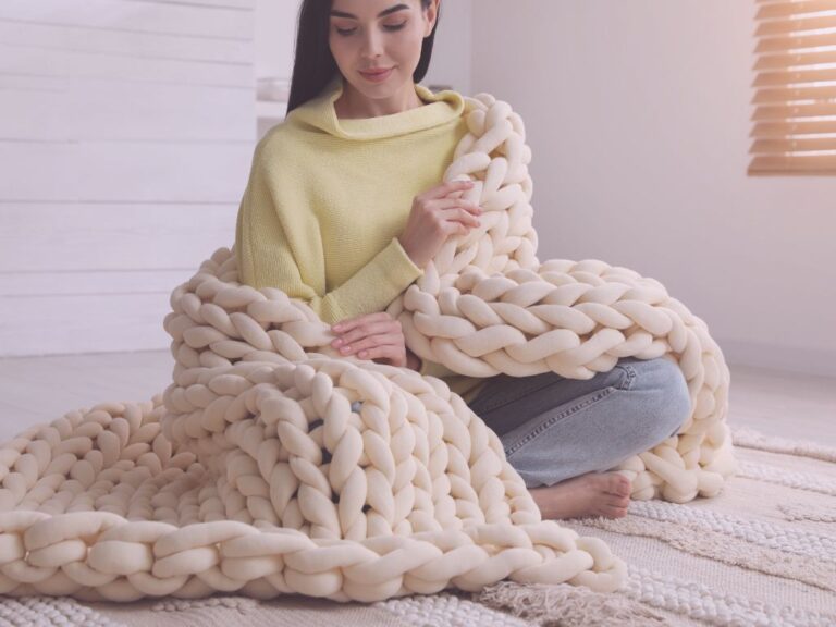 Femme assise au sol, enveloppée dans un plaid, moment de douceur et d’ancrage intérieur