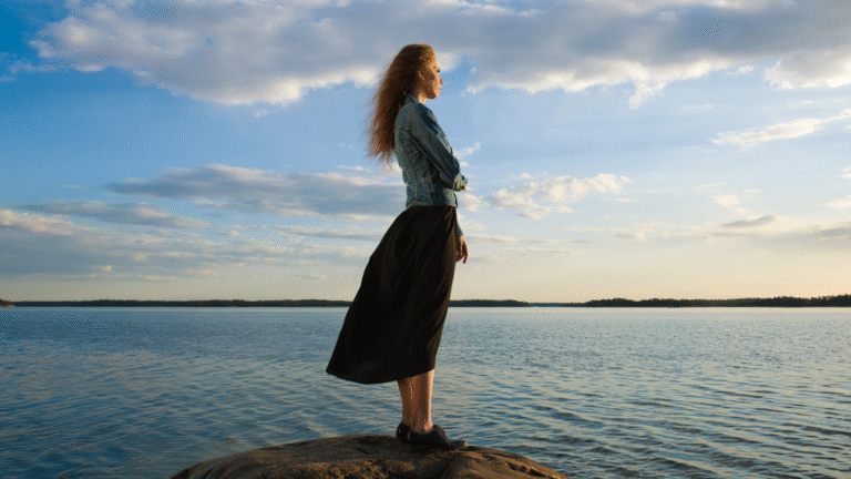 Femme regardant l’horizon en silence, symbole de recentrage et de sérénité retrouvée.