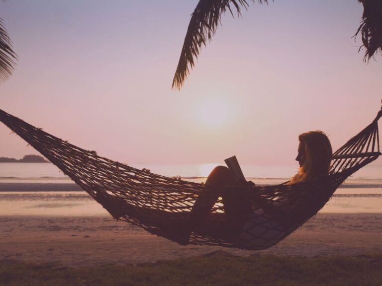 Silhouette lisant dans un hamac, ombre végétale reposante. Femme au bord de l’eau en méditation, symbole de s’autoriser à être soi