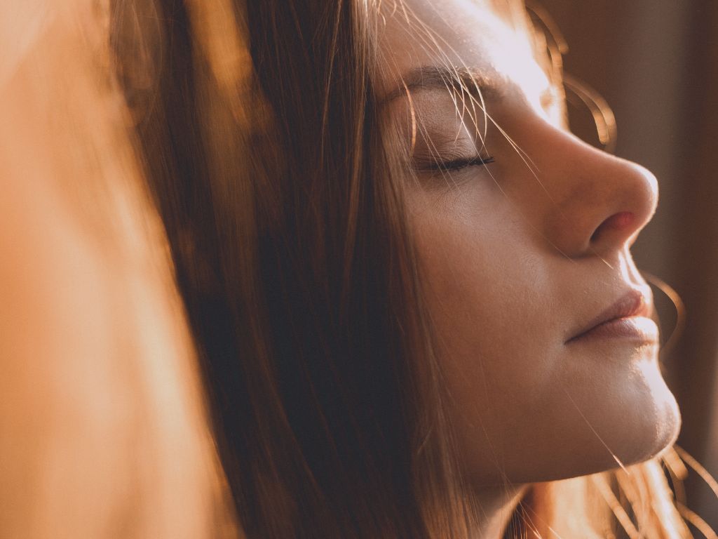 Femme les yeux fermés avec une lumière chaude sur le visage