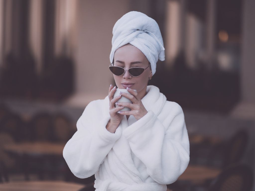 Femme en peignoir, yeux fermés, tenant une tasse au lever du jour, routine matinale préserver son énergie septembre