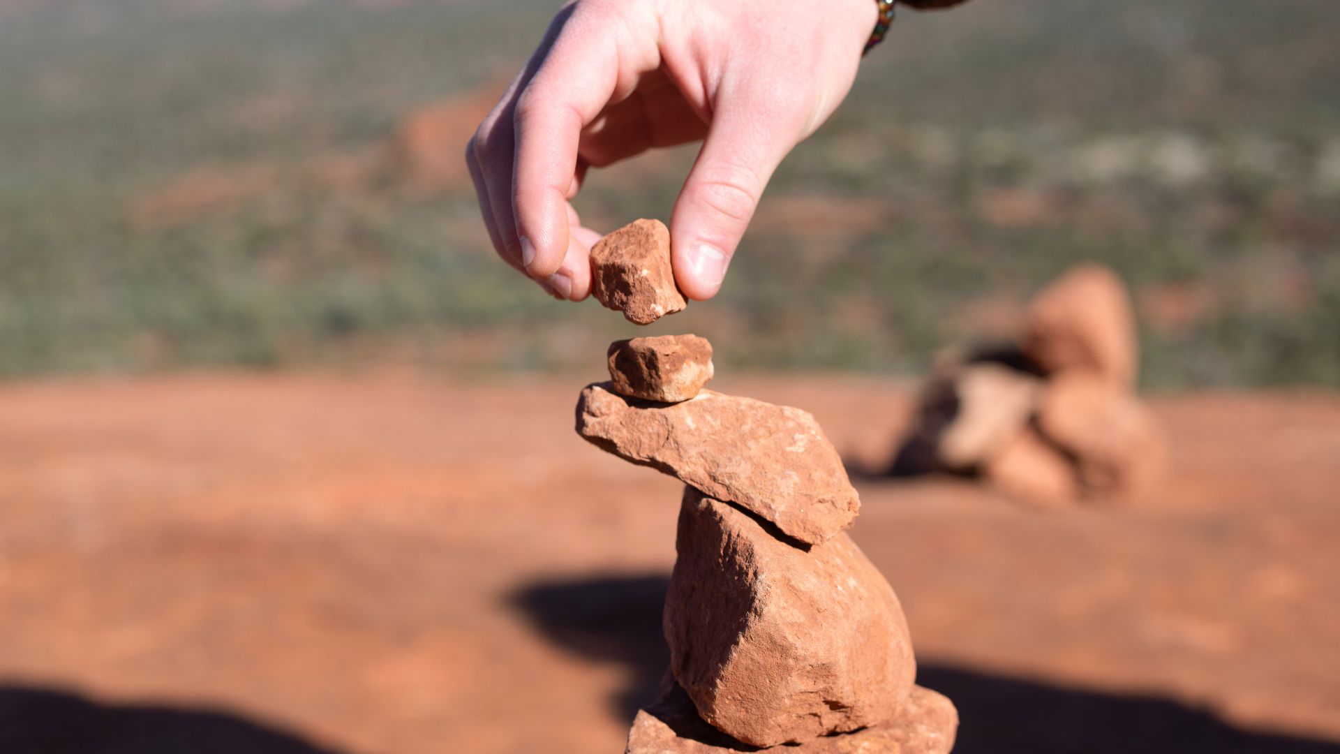Main déposant une pierre au sol, symbole de libération et de délestage des fardeaux intérieurs