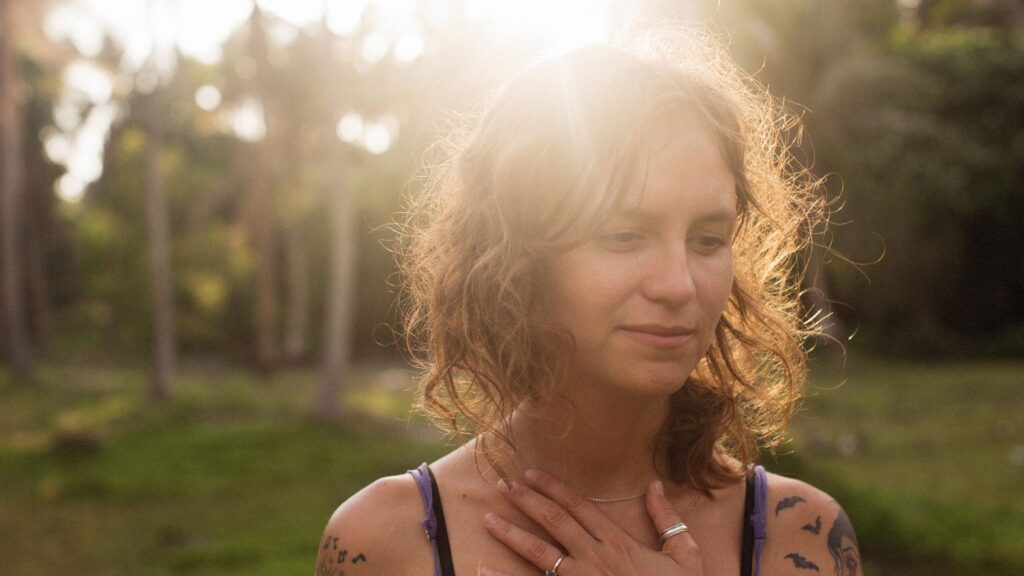 Femme posant une main sur son cœur pour écouter son corps, geste de douceur et de reconnexion