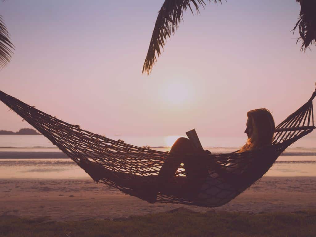 Silhouette lisant dans un hamac, ombre végétale reposante